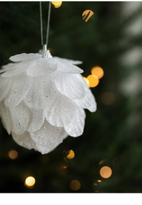 Close-up of white pine cone Christmas ornament with glitter and silver hanging loop