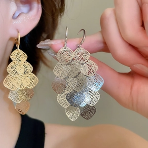 Detailed view of gold and silver diamond geometric tassel earrings with layered hollow mesh