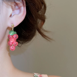 Detailed close-up of pink and green resin grape cluster earrings worn by a model