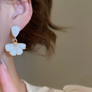 Gros plan sur des boucles d'oreilles fleur en émail blanc et placage doré élégant