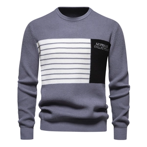 Detail of grey crewneck knit sweater featuring white stripe and black logo patch