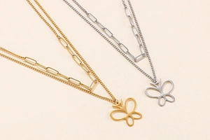 Detail of double-layer necklace featuring a hollow butterfly pendant in gold and silver finish