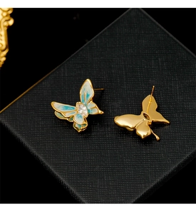 Macro view of butterfly earrings with gold plating, blue enamel wings, and zircon center