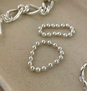 Macro detail of minimalist 925 sterling silver beaded rings and chunky curb chain jewelry