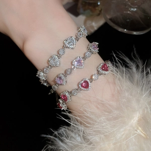 Detailed view of silver heart bracelets with pink and red zircon stones on a model