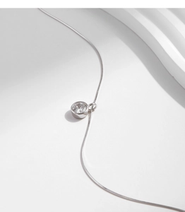 Macro detail of a sparkling bezel-set solitaire pendant with a sleek silver snake chain