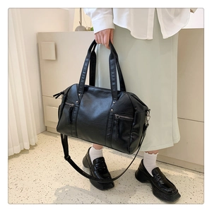 Detailed macro view of black Boston bag featuring silver studs and vertical zipper pockets