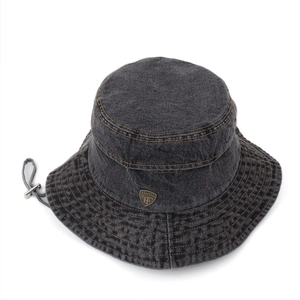 Detail of grey denim bucket hat with yellow contrast stitching and metal shield emblem
