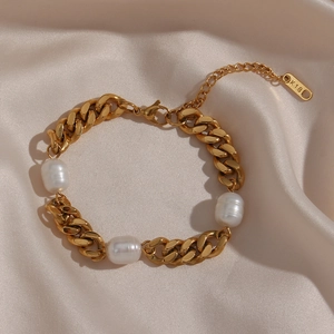 Detail of gold-plated Cuban chain bracelet with three white pearls on velvet fabric