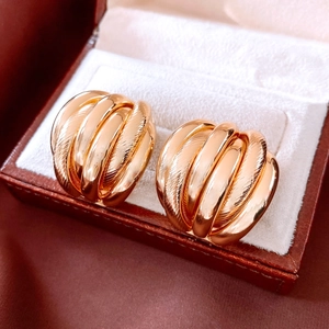 Gros plan de créoles torsadées dorées présentées dans un écrin à bijoux en velours chic