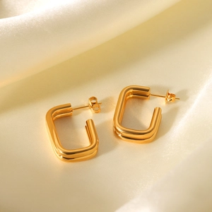 Close-up of double-layer gold rectangle earrings on a cream silk background
