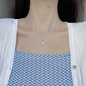 Detail of silver heart lock necklace with blue zircon gemstone worn on a model