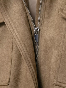 Detailed close-up of premium metal zipper and tan faux suede fabric texture on jacket