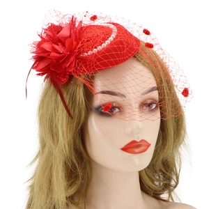 Close-up of red fascinator hat featuring elegant feathers, pearls and face veil