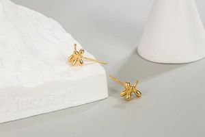 Detail of golden balloon dog stud earrings showing S925 silver hallmark and polished finish