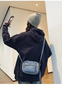 Close-up of blue denim crossbody bag with zipper detail on a model in daily life