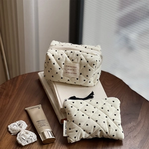 Quilted heart print corduroy cosmetic bag set on a wooden table with chic accessories