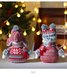 Close-up of plush Christmas snowman figurines with red and grey knitted snowflake sweaters