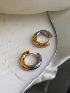Macro detail of high-quality two-tone gold and silver chunky hoop earrings in a minimalist style