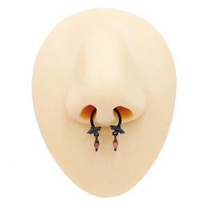 Detail of black metal bat nose ring with red teardrop pendant on a model's nose
