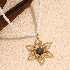 Detail of 18K gold petal pendant with natural stone on white beaded necklace