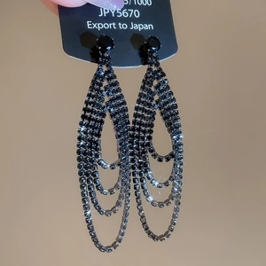 Détail de boucles d'oreilles de luxe avec pompons en strass noirs et cercles superposés