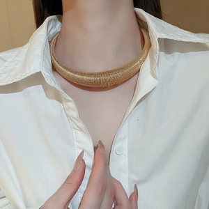 Detail of gold chunky circular choker necklace with fine spiral texture worn on neck