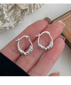 Detail of s925 silver geometric hoop earrings with twisted texture held by a hand