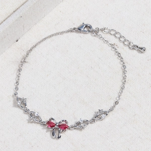 Detailed macro view of silver bow bracelet with red pear-shaped heart zircons