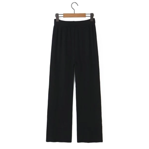 Close-up of black knitted wide-leg trousers with elastic high waist and ribbed texture