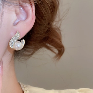 Detailed close-up of a golden pearl and rhinestone earring worn on a female model