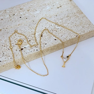 Elegant gold cocktail glass necklace with zircon inlay on a minimalist stone base