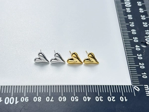 Macro detail of 15mm gold and silver heart stud earrings with size measurement tool