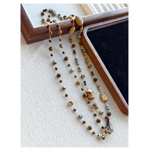 Detail of bohemian long necklace with natural tiger eye, jasper and gold beads
