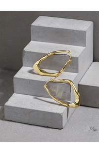 Close-up of golden irregular wavy hoop earrings displayed on grey minimalist textured steps