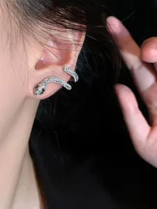 Gros plan de la boucle d'oreille serpent en argent avec cristaux et yeux verts