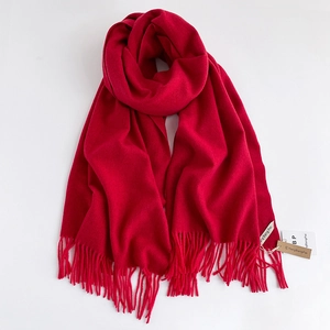 Dettaglio di una sciarpa rossa effetto cashmere con frange morbide ed etichetta del marchio