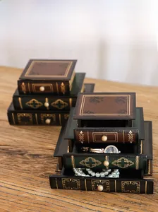 Macro shot of vintage book-style jewelry boxes with drawers, gold floral details and pull handles