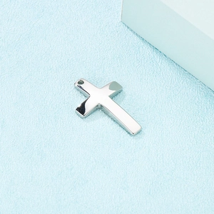 Detailed view of a polished silver stainless steel cross pendant on a textured surface