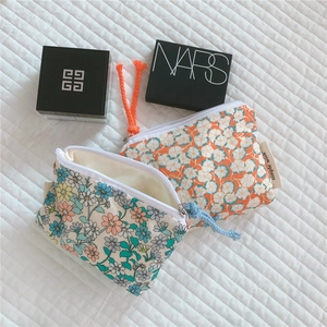 Detailed view of floral cotton mini pouches with woven zip pulls and side label