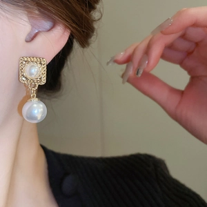 Nahaufnahme von Vintage-Perlenohrringen mit eleganten goldenen Prägedetails an einem Model