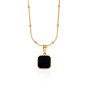 Close-up of golden beaded chain with a polished black square pendant on white background