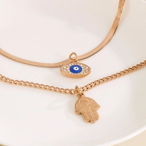 Detail of gold layered necklace with blue evil eye pendant and Hamsa hand charm