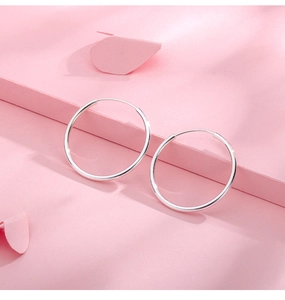 Close-up of minimalist S999 sterling silver hoop earrings with glossy metallic finish