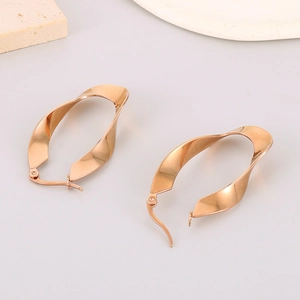 Detailed shot of rose gold twisted geometric earrings on minimalist props