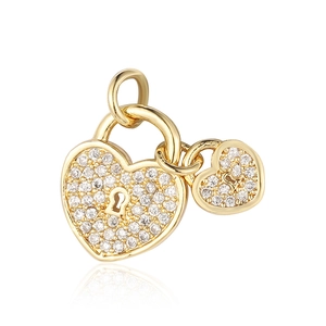 Macro detail of gold heart lock pendants with cubic zirconia and ornate keyhole pattern