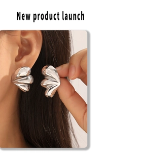 Close-up of elegant silver wing-shaped pleated stud earrings worn on the earlobe