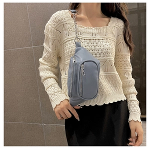 Détail du sac de poitrine en cuir PU bleu-gris avec trois zips et bandoulière chaîne