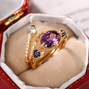 Macro detail of a vintage snake ring with purple oval stone and blue accents in a red box