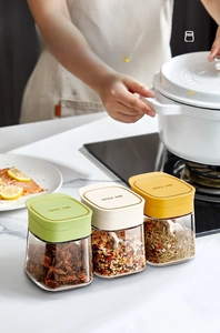 Three-piece glass spice jar set with colored lids and spoons for kitchen seasoning